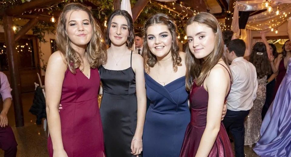 Quattro studentesse in abbigliamento formale posano insieme durante una festa al Kaipara College.
