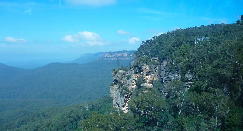 Vista su scogliere rocciose sopra una valle boscosa sotto un cielo blu senza riferimento diretto alla Mount Barker High School.