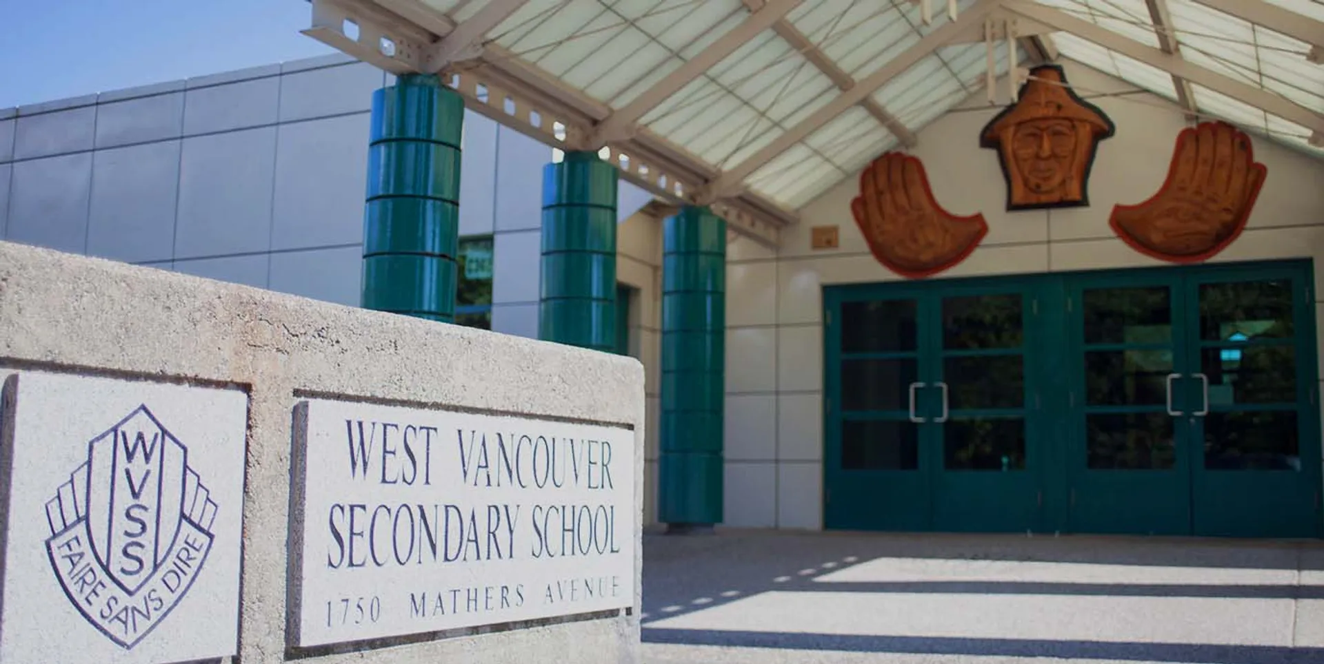 L'edificio scolastico della West Vancouver Secondary School con il suo tetto caratteristico e le grandi finestre è circondato da un cartello con il nome della scuola e l'indirizzo.