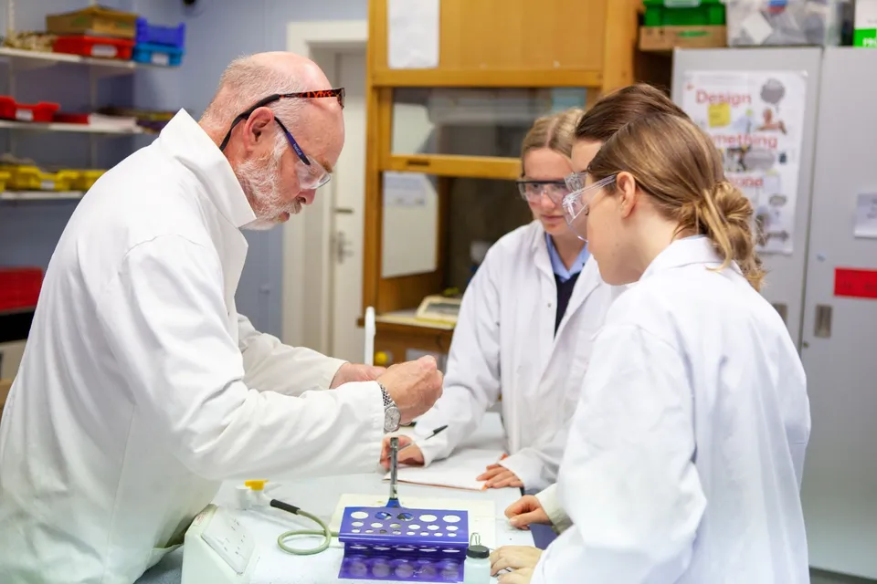 Un uomo anziano spiega a due studentesse nel laboratorio del campus della Torquay Girls Grammar School.