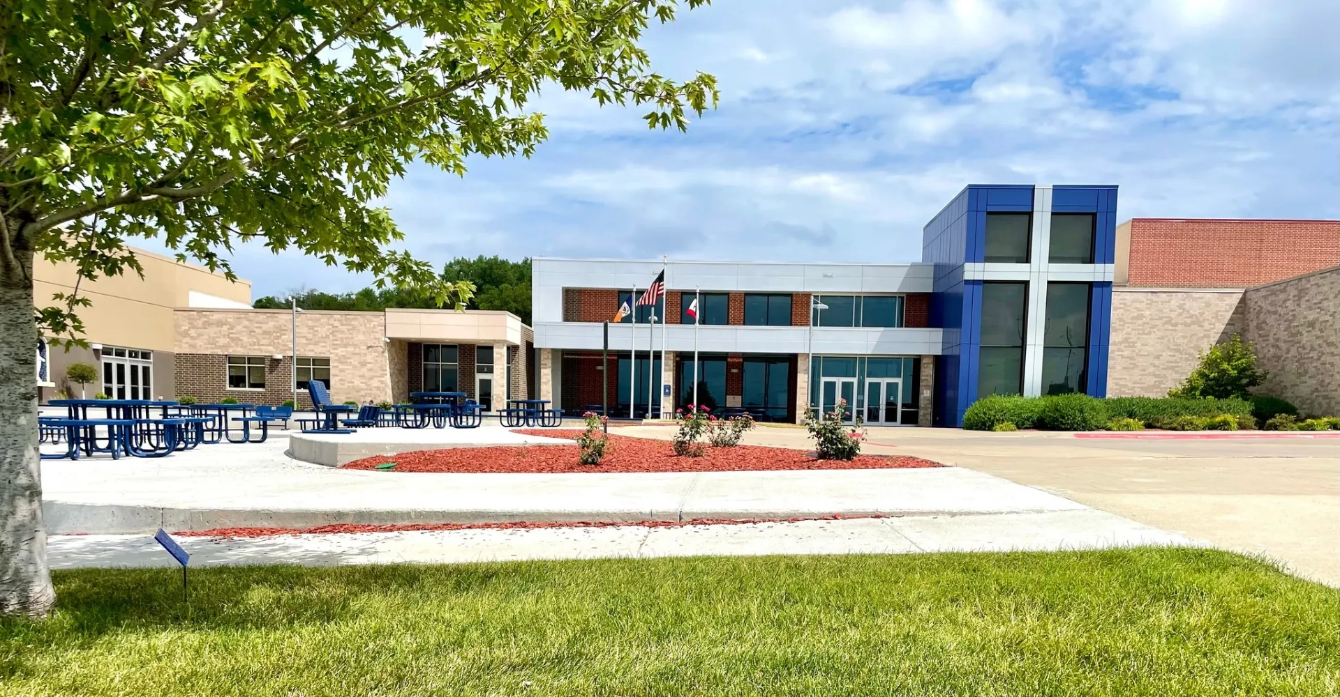 L'edificio moderno a più piani della Bishop Heelan Catholic High School è circondato da alberi verdi e da un prato ben curato.