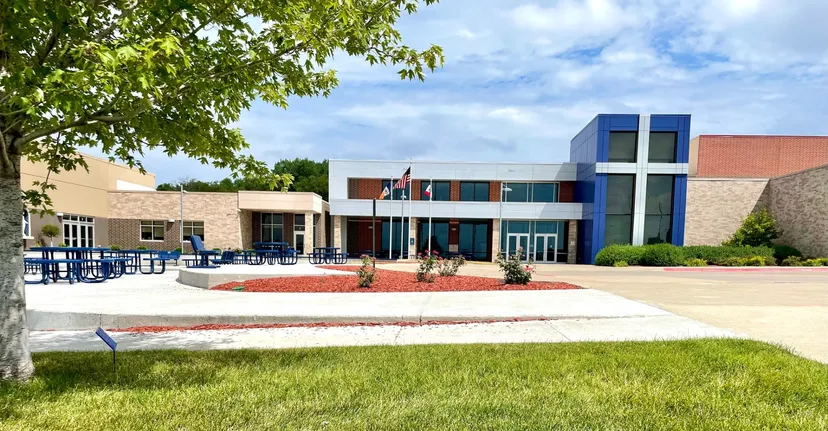 L'edificio moderno a più piani della Bishop Heelan Catholic High School è circondato da alberi verdi e da un prato ben curato.