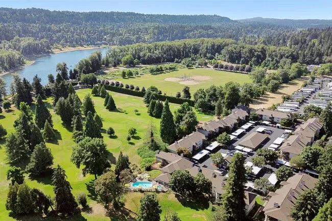 Vista aérea del entorno de Gladstone High School con un río, campos deportivos, edificios residenciales y bosques.