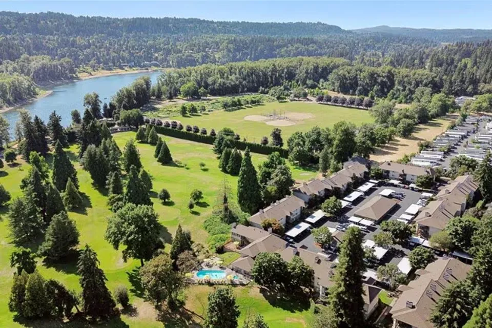 Vista aerea dei dintorni della Gladstone High School con un fiume, campi sportivi, edifici residenziali e colline alberate.