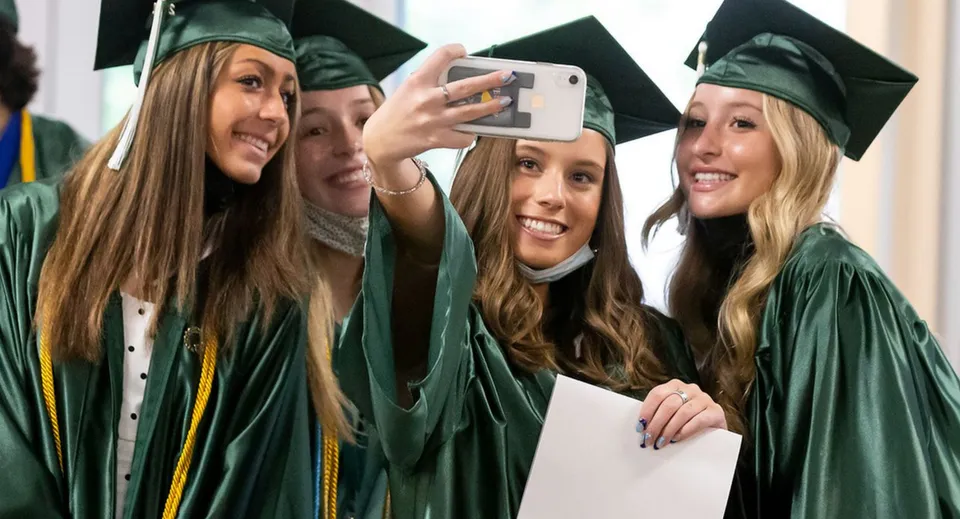 Quattro studentesse della Trinity Bay State High School si scattano un selfie insieme con le toghe verdi dopo la cerimonia di diploma.
