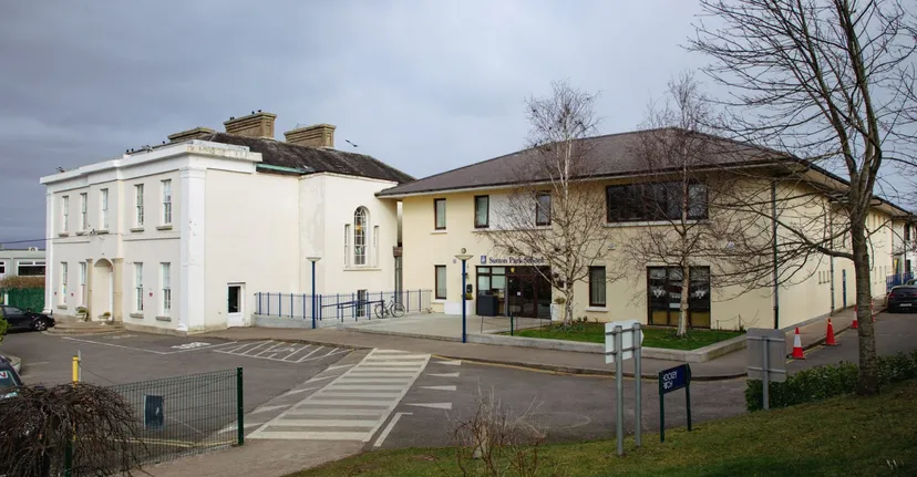 L'edificio bianco a più piani con tetto a spiovente della Sutton Park School a Dublin è circondato da alberi spogli.