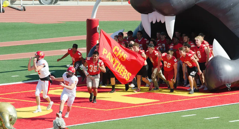 Un gruppo di studenti in uniforme rossa con una grande bandiera rossa sul campo sportivo del Chico Unified School District.
