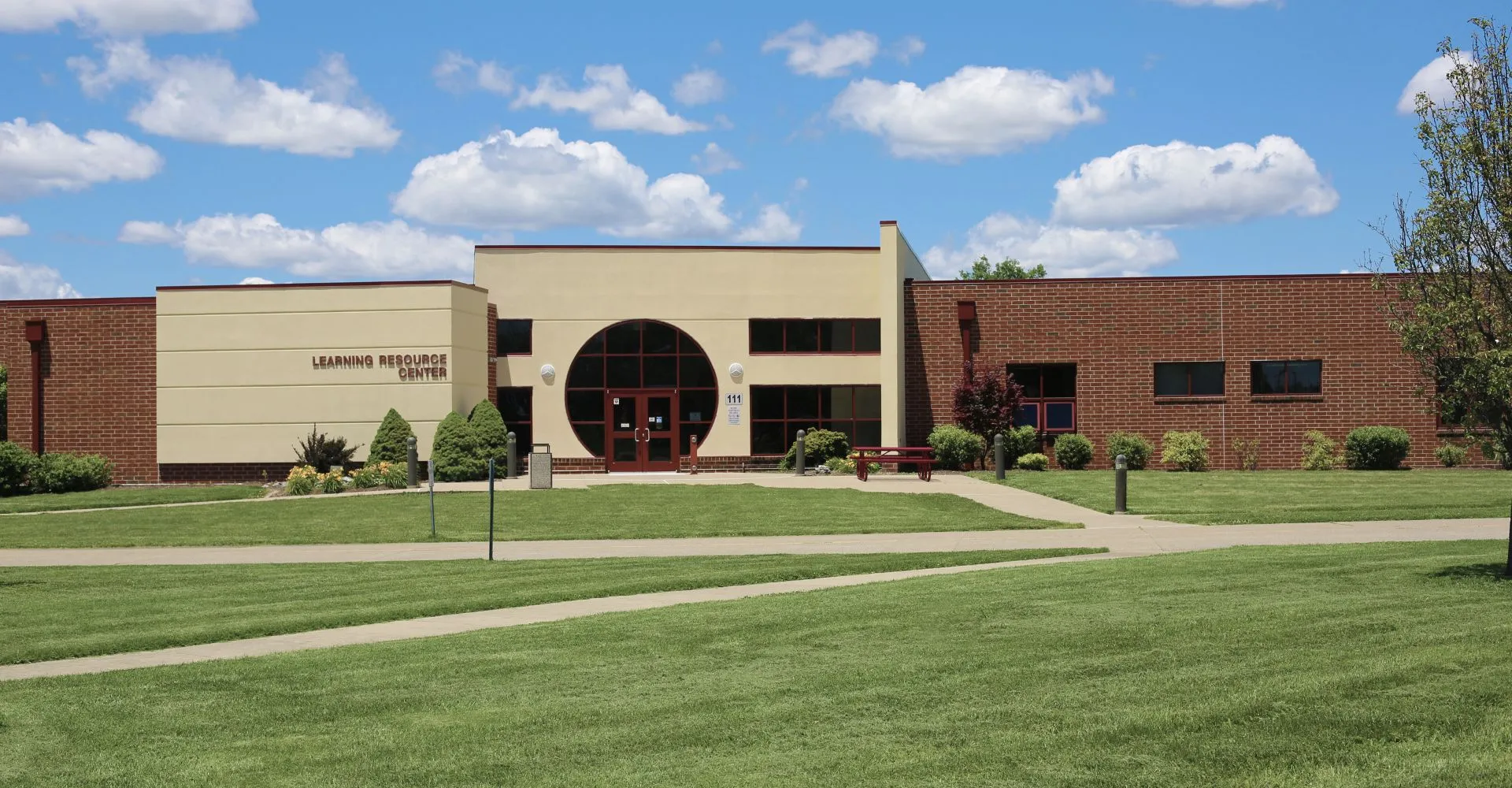 Il moderno edificio in mattoni dell'Illinois Eastern Community Colleges con un ingresso ad arco su un prato ben curato e circondato da vegetazione verde.