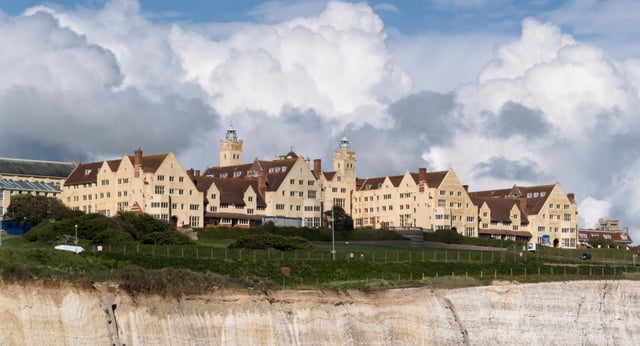 L'edificio storico della Roedean School si erge su una scogliera sotto un cielo nuvoloso.