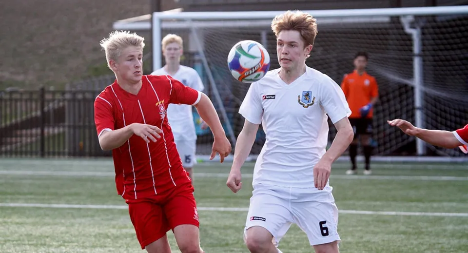 Due studenti della Westlake Boys High School giocano a calcio sul campo sportivo e si contendono il pallone.