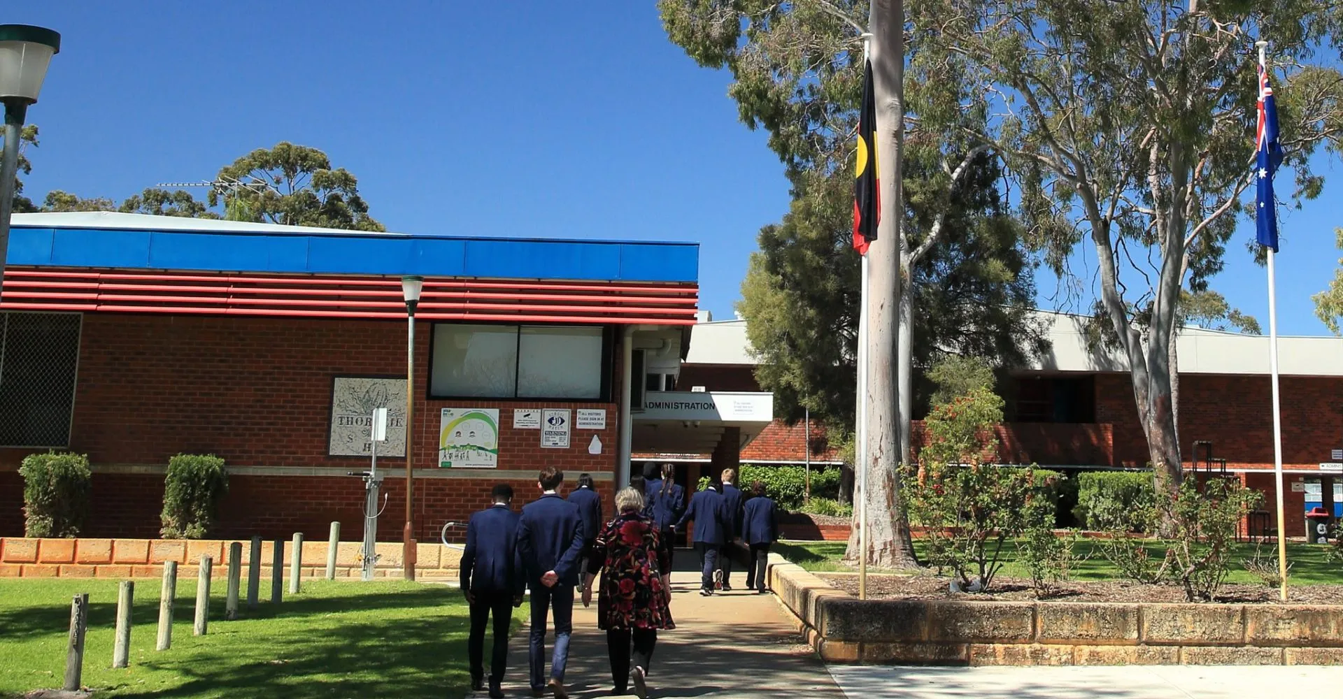 Un gruppo di studenti cammina su un sentiero erboso verso l'edificio in mattoni della Thornlie Senior High School.