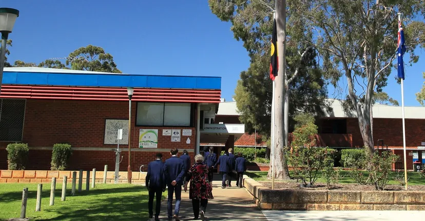 Un gruppo di studenti cammina su un sentiero erboso verso l'edificio in mattoni della Thornlie Senior High School.
