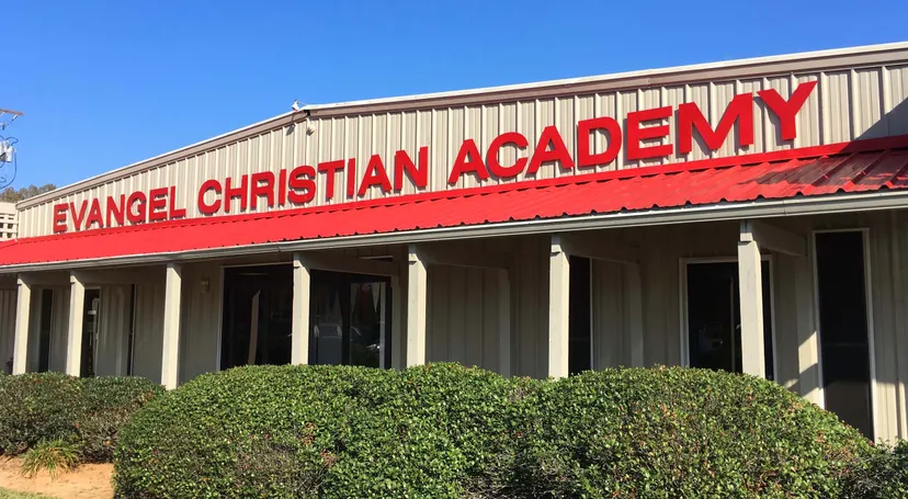 L'edificio principale della Evangel Christian Academy con il tetto rosso è circondato da cespugli e alberi.