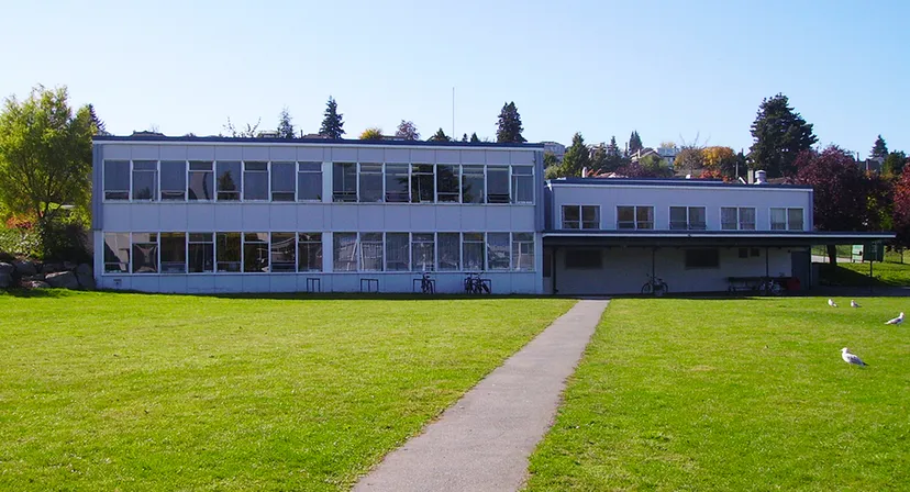 L'edificio moderno in vetro della Prince of Wales Secondary School si trova su un prato verde sotto un cielo azzurro.