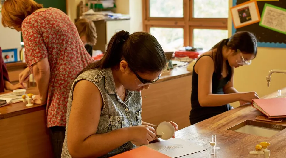 Tre studentesse della Yehudi Menuhin School siedono a un tavolo impegnate a leggere e scrivere.