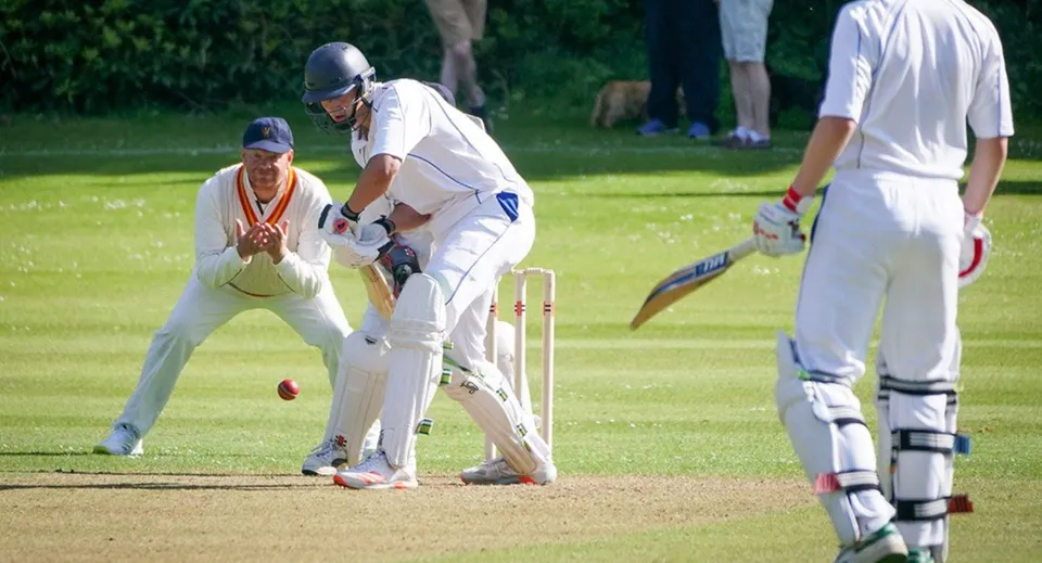 Studenti del Stratford College giocano una partita di cricket su un campo verde.