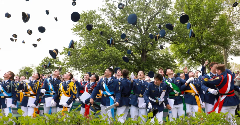 Studenti della Indiana Private Highschool indossano uniformi tradizionali giapponesi e lanciano i loro cappelli in aria su un prato.
