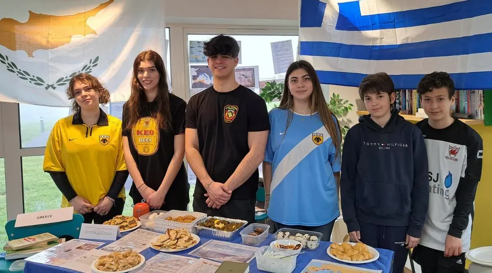 Studenti della St. Michael’s School si trovano davanti a una mostra con vari alimenti e decorazioni colorate.