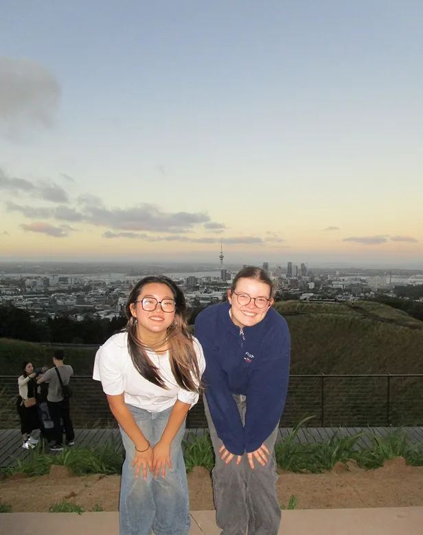 Dos chicas en un mirador sobre la ciudad de Auckland con la Sky Tower al atardecer