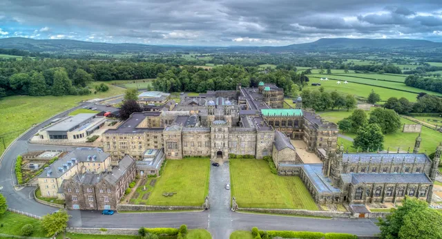 Das mittelalterliche Schloss auf dem Gelände des Stonyhurst College ist von grüner Landschaft und Hügeln umgeben.