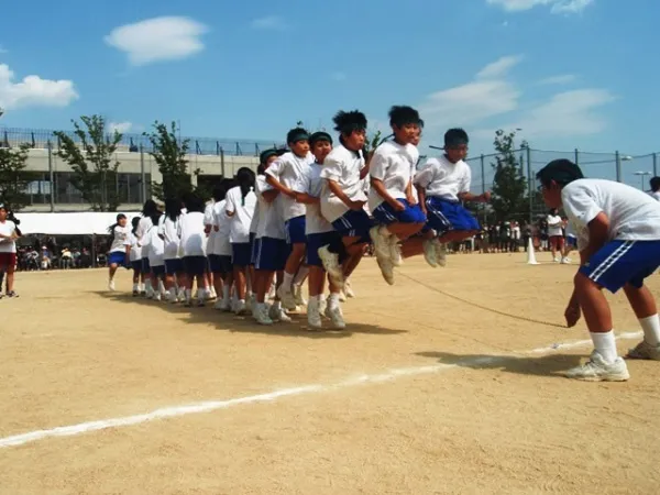 Schüler der Hinodegakuen Senior High School springen gemeinsam auf einem Sportplatz Seil.