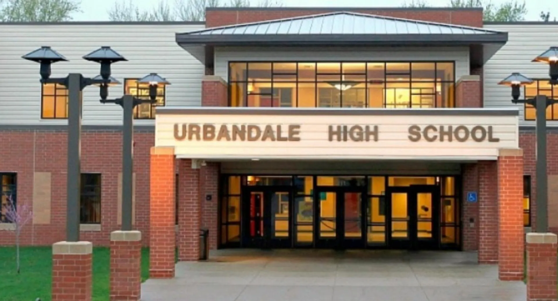L'edificio in mattoni con la scritta Urbandale High School è circondato da lampioni e da un'area d'ingresso pavimentata.