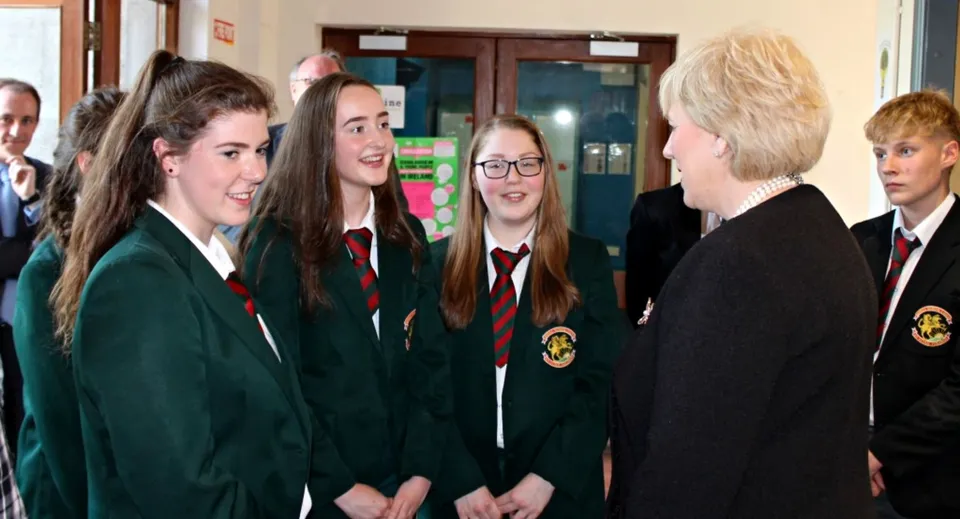 Studenti della Royal School Cavan chiacchierano nel corridoio della scuola indossando la loro divisa scolastica con giacche verdi e nere.