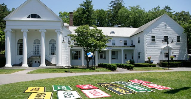 Der gepflegte Rasen und bunte Schilder vor dem kolonialstil Gebäude auf dem Campus der Dana Hall School.