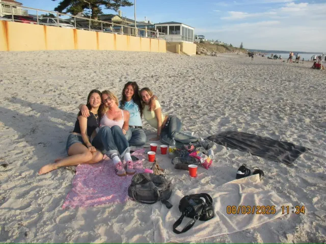 Gruppo di ragazze sedute su un telo da spiaggia in Australia al tramonto