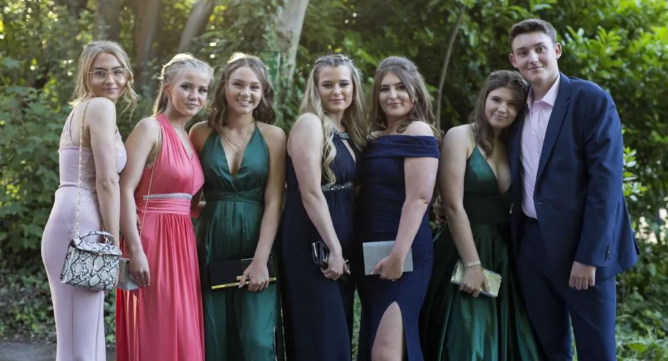 Un gruppo di persone ben vestite si trova insieme in un'area verde esterna della Ackworth School.