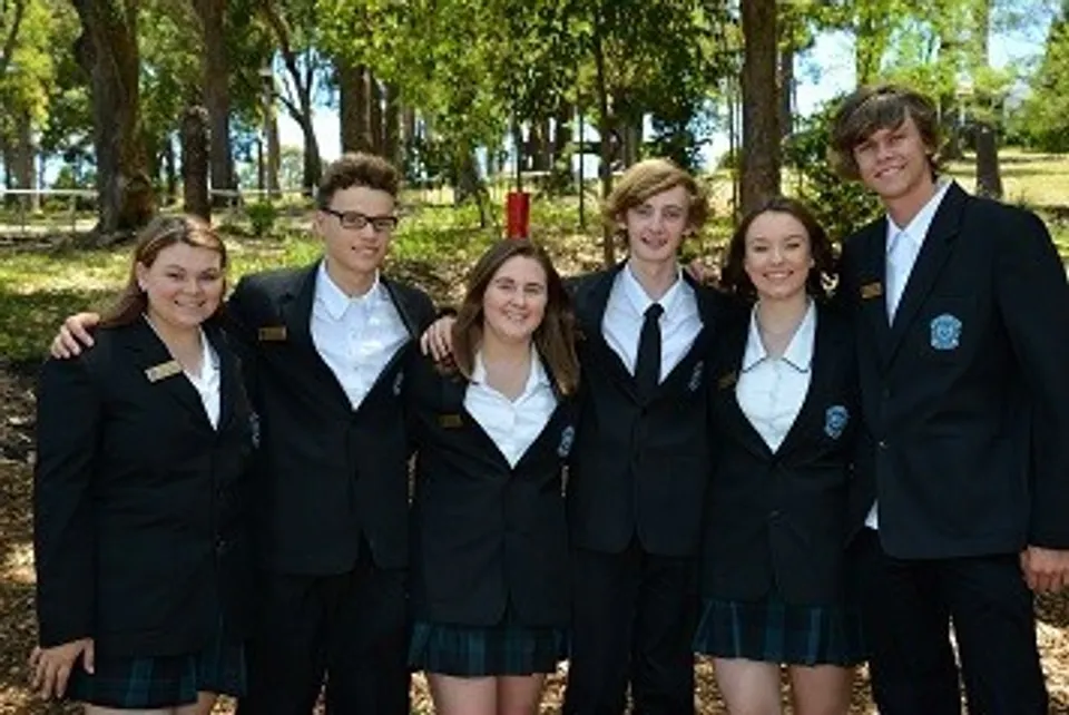 Un gruppo di studenti della Cardiff High School in divisa scolastica si trova in un bosco e posa per una foto.