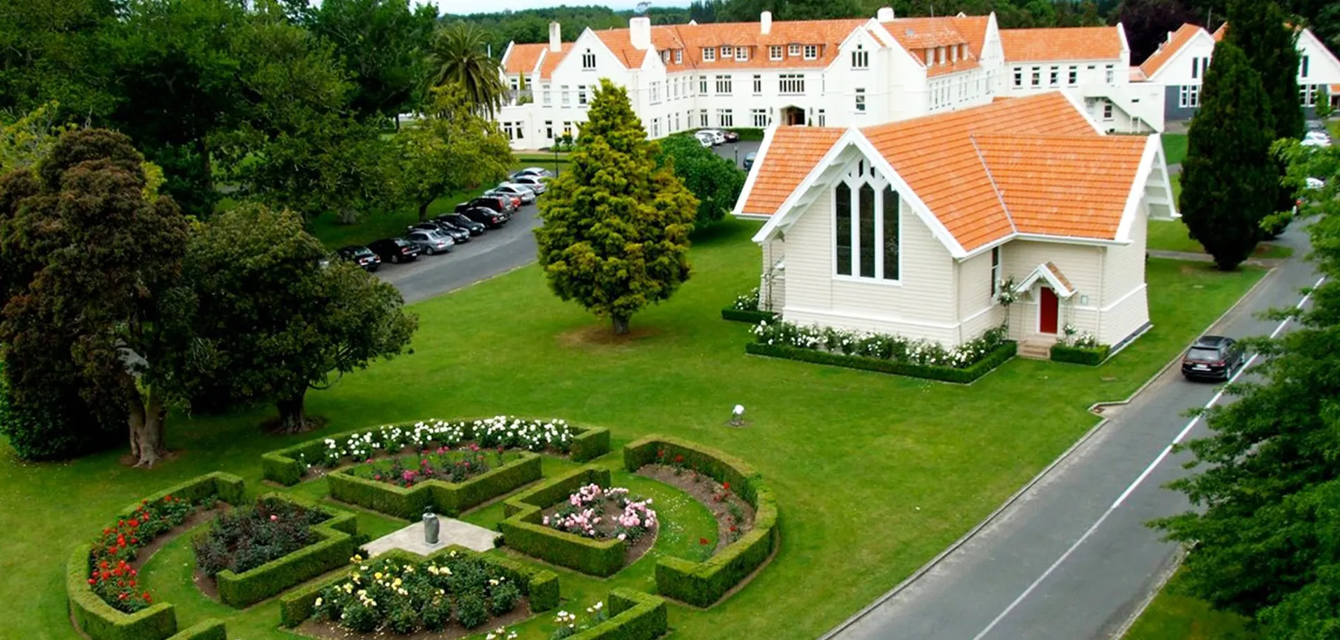 L'edificio scolastico simile a un castello della St. Peter's School Cambridge è circondato da un giardino ben curato con siepi e aiuole.