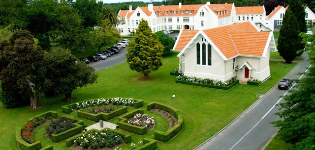 L'edificio principale storico della St. Peter's School Cambridge circondato da un giardino curato con aiuole e viali.