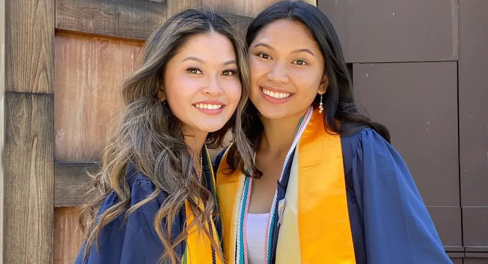 Due studentesse del Chino Valley Unified School District sono in piedi davanti a un edificio in legno e indossano toghe di diploma colorate.