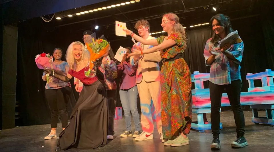 Studenti della Maharishi School sul palco in costumi colorati durante uno spettacolo.
