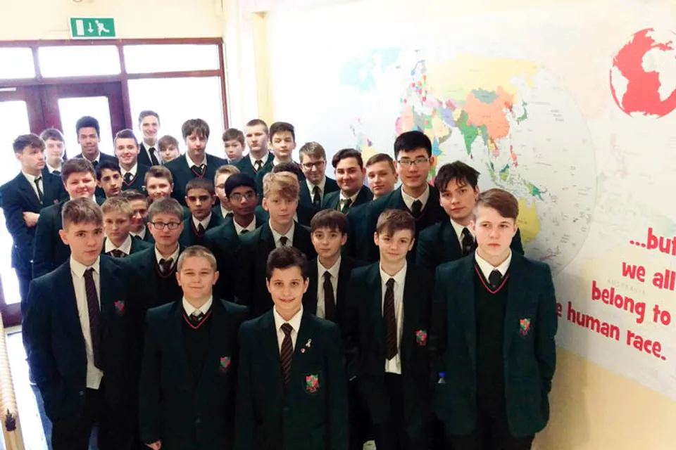 Un gruppo di studenti della St. Joseph's Secondary School sta in piedi davanti a una mappa del mondo alla parete.
