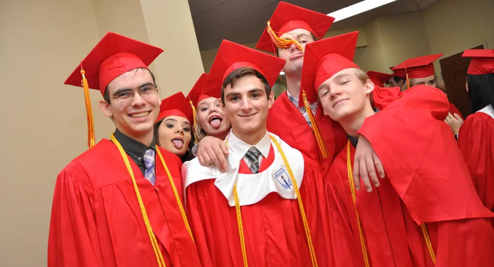 Un gruppo di diplomati della Orangewood Christian School in posa con toghe rosse davanti a uno sfondo semplice.