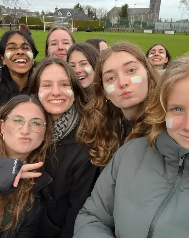 Gruppo di ragazze con la faccia dipinta si fa un selfie a bordo di un campo sportivo
