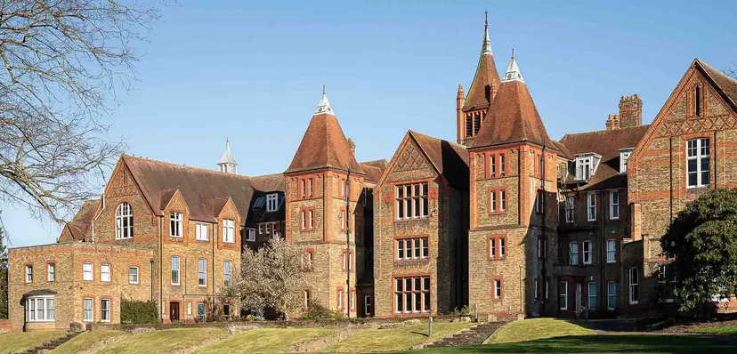 L'edificio storico in mattoni con dettagli architettonici decorati nel campus della St. Margaret’s School è circondato da una verde vegetazione.