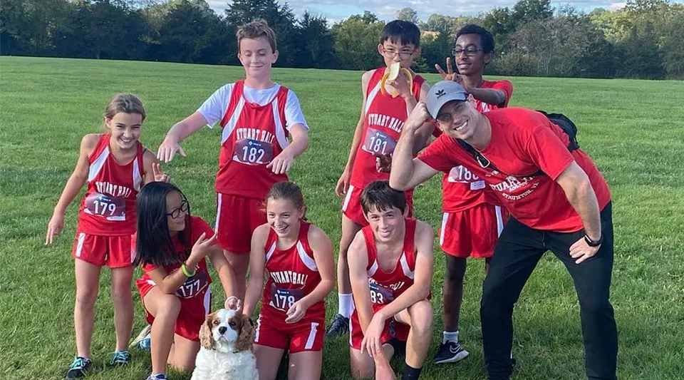 Un gruppo di giovani atleti in maglia rossa posa sul campo all'aperto all'interno del campus della Stuart Hall School.