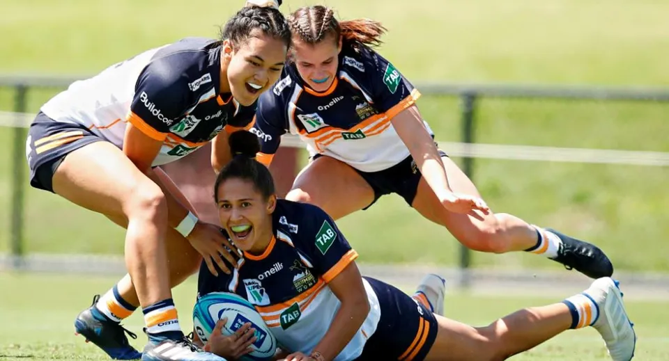 Un gruppo di giocatrici di rugby esegue un placcaggio sul campo da gioco della Queen Margaret's School for Girls.