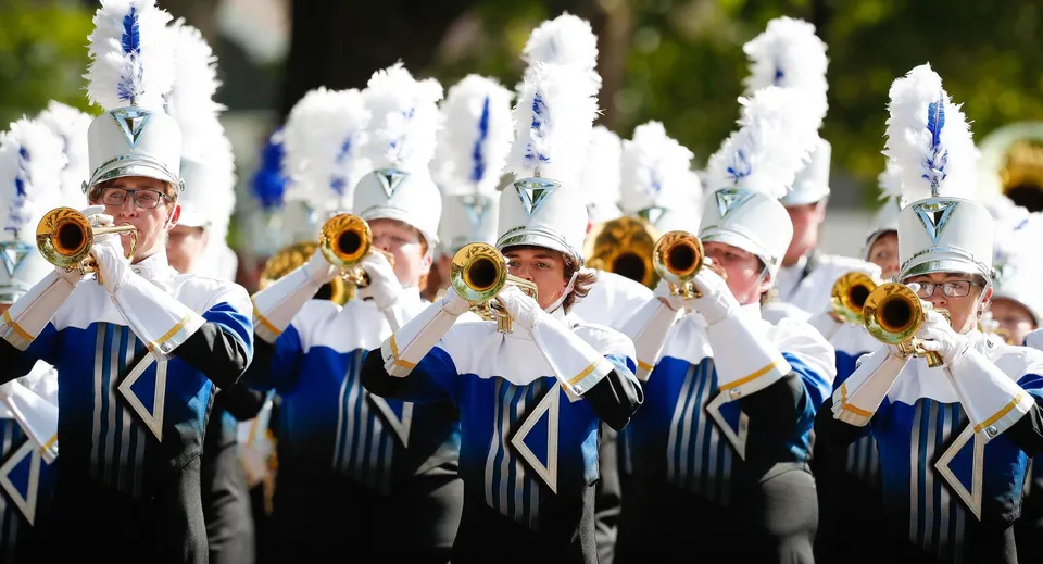 La Marching Band del Lisgar Collegiate Institute suona all'aperto davanti a uno sfondo verde.