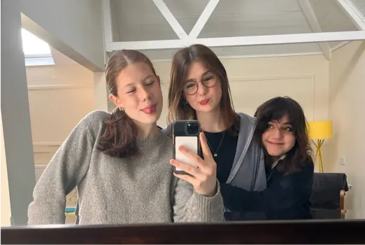 Drei Mädchen machen ein Spiegel-Selfie in einem Zimmer in England
