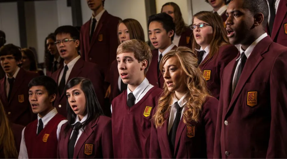 Studenti della Heritage Christian Academy sono insieme in un contesto formale e cantano in tunica da coro.