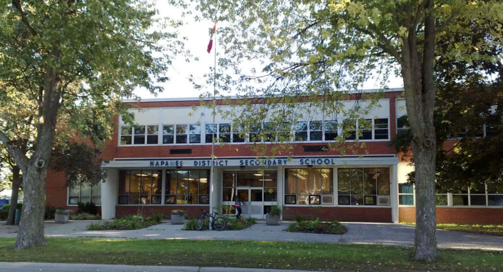 L'edificio in mattoni a due piani della Napanee District Secondary School si trova su un prato circondato da alberi.