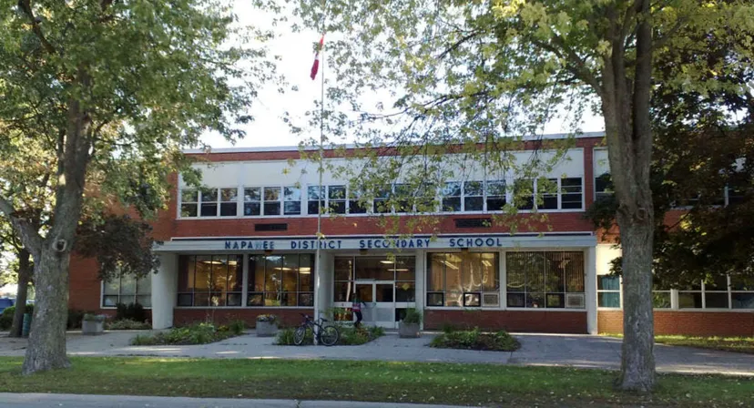 L'edificio in mattoni a due piani della Napanee District Secondary School si trova su un prato circondato da alberi.