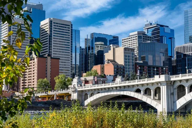 Skyline di una città canadese con grattacieli e un ponte ad arco sul fiume in una giornata di sole