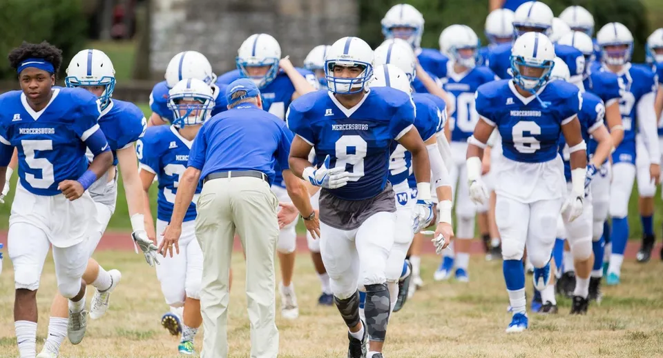 Un gruppo di giocatori di calcio in bianco e blu sul campo sportivo della Mercersburg Academy.
