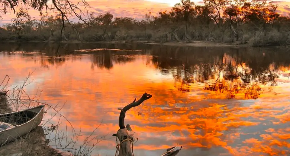 Un lago calmo con un tramonto autunnale e la vegetazione circostante nel terreno della Roxby Downs Area School.