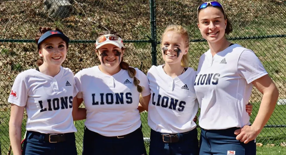 Quattro studentesse indossano magliette bianche con il logo dei Lions e si trovano sul campo sportivo della Kent School.